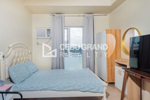 Double bed with a tufted headboard beside the window and wardrobe