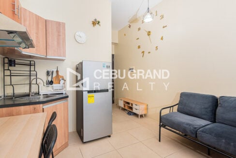 Sink, range hood and refrigerator beside a loveseat and gold wall clock