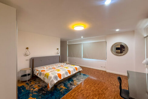 Master bedroom at the Regency Crest condo with a gray upholstered bed and blue rug