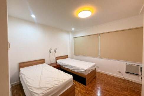 Second bedroom with two single beds and window-type air conditioning