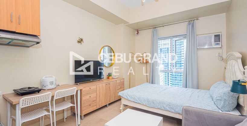 Furnished 31st floor studio at Avida Riala Tower 3 with bed, sofa and kitchen corner