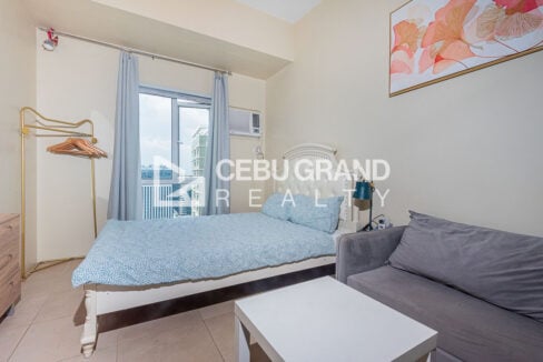 Double bed by the window with a grey sofa and white coffee table