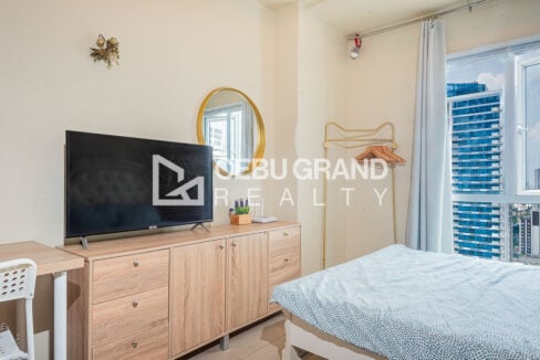 Timber sideboard with flat-screen TV and gold mirror in an Avida Riala studio