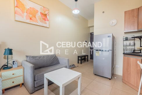 Grey sofa, bedside table and stainless refrigerator near the studio entry
