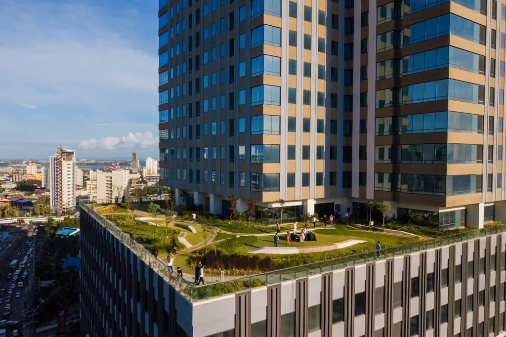 Landscaped podium deck with lawns and walking paths at the base of Cebu Exchange Tower