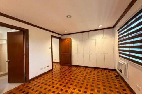 Bedroom with a wall of white built-in wardrobes and parquet floors