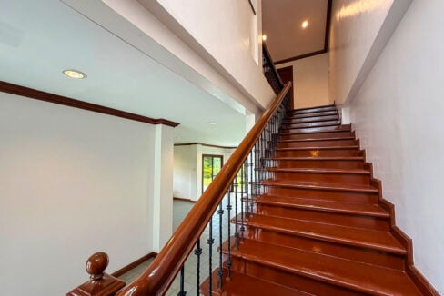Wood staircase with wrought-iron balusters rising to the upper floor of the Mandaue house