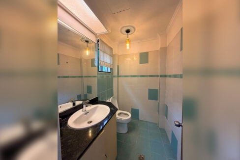 Bathroom with white and teal tiles, a granite counter and a pendant light