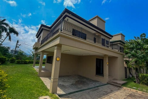 Corner view of the house showing the carport columns and the upper-floor balcony railing
