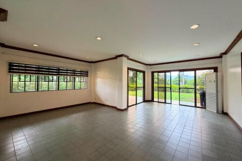 Empty living area with grey floor tiles, recessed lights and sliding doors to the garden