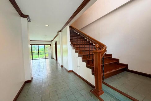 Ground-floor hallway beside a wooden staircase, leading to glass doors onto the garden