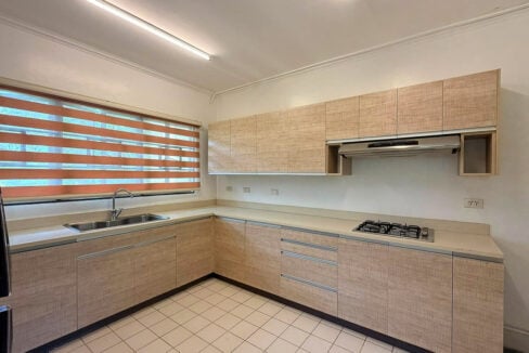 Kitchen with light wood-grain cabinets, a gas hob, range hood and sink under a window