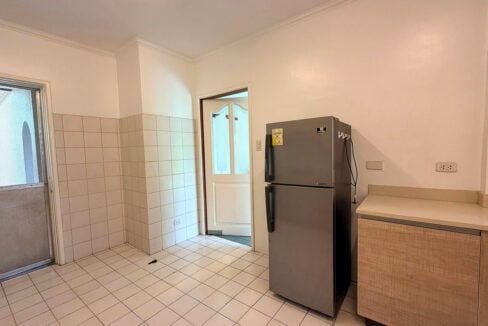 Tiled second kitchen room with a refrigerator and a screen door