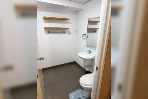 Bathroom with pedestal sink, mirror and timber shelving