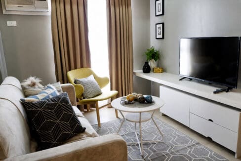 Living area with sofa, accent chair and wall-mounted flatscreen TV
