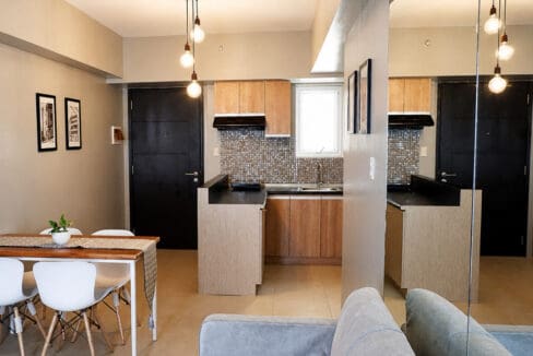 Dining table and kitchen with pendant lighting and mosaic backsplash