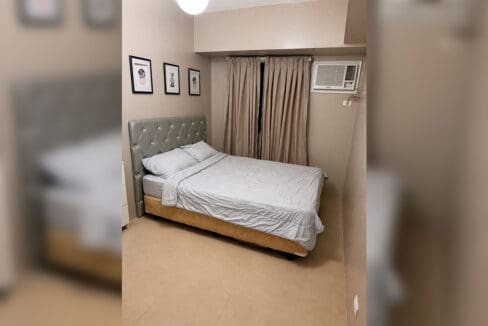Bedroom with tufted headboard, window-type air-conditioning and framed art