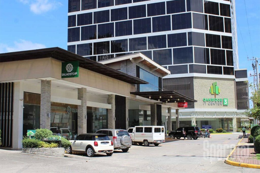 Oakridge IT Center facade with retail spaces and parked cars in Cebu Business Park