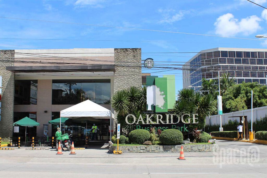 Main entrance signage of Oakridge Business Park with landscaped greenery and guard post