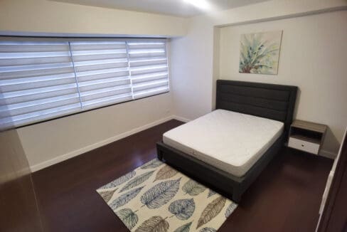 Alcoves condo for rent — queen bedroom on dark hardwood flooring
