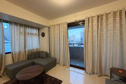 Queen bed with upholstered headboard in the bedroom of 1BR condo at The Alcoves
