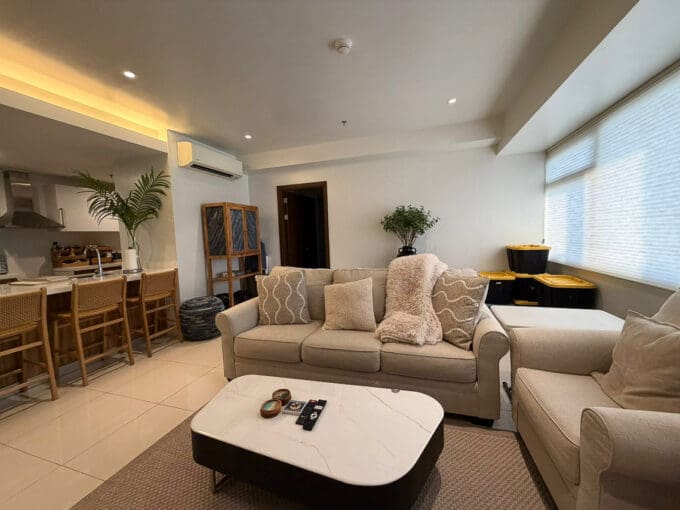 Second lounge zone with wall-mounted flatscreen TV and media console in 1BR at The Alcoves