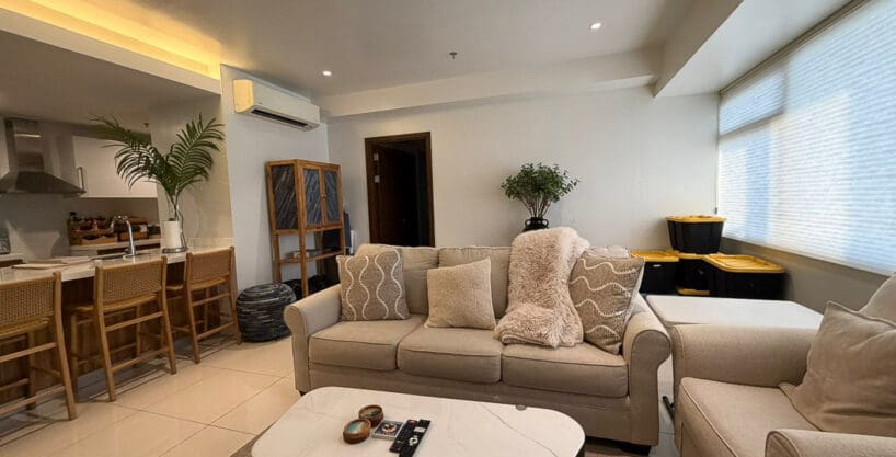 Second lounge zone with wall-mounted flatscreen TV and media console in 1BR at The Alcoves