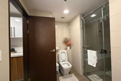 Bathroom with black marble vanity and glass-enclosed rain shower at The Alcoves 1BR
