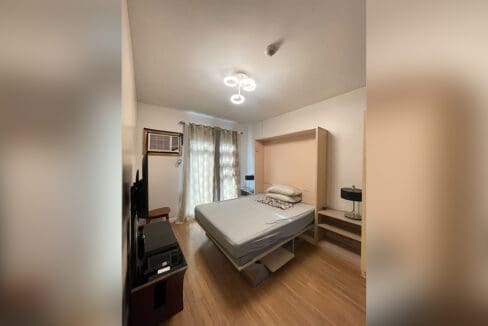 Bedroom with wall-mounted flatscreen TV and window aircon at Solinea Tower 1 1BR