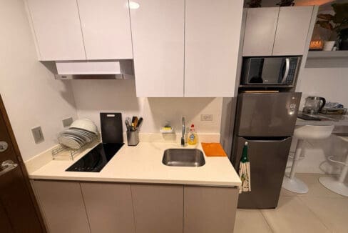 Utility area with wall-mounted sink and Samsung front-load washer at 38 Park Avenue studio