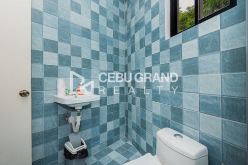Small blue-tiled toilet with a wall-hung sink