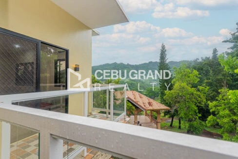 Glass-railed balcony with a view over the trees to the hills of Binaliw