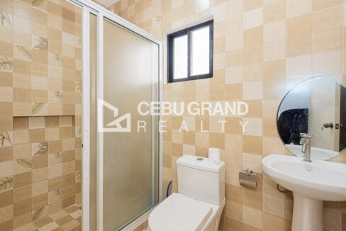 Ensuite bathroom with leaf-pattern tiles, a glass shower enclosure and round mirror