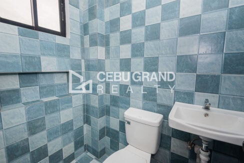 Blue-tiled bathroom with a wall-hung sink and window