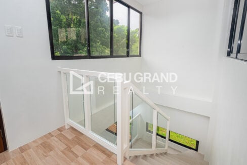 Top-floor landing with wood-look tiles and a glass-railed staircase