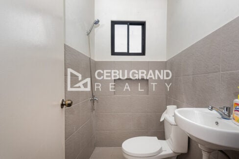 Grey-tiled bathroom with a handheld shower and wall-hung sink