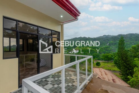 Top-floor balcony under the red roof edge, facing the green hills of San Lorenzo Woodlands