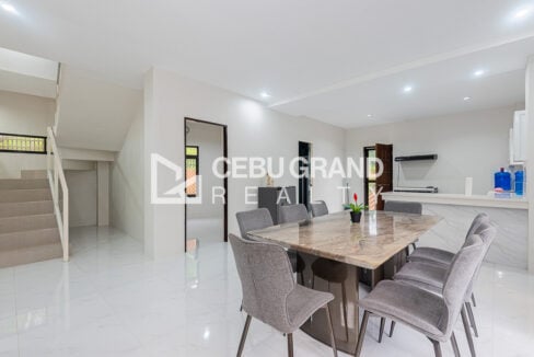 Marble-top dining table and grey upholstered chairs near the breakfast counter