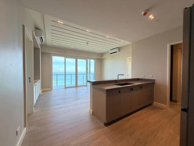 Empty living room with sliding doors to sea view balcony at Aruga Resort 6F condo
