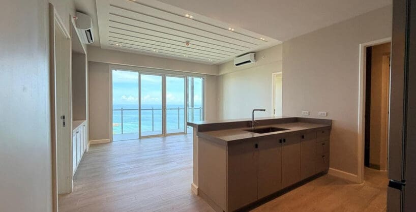 Empty living room with sliding doors to sea view balcony at Aruga Resort 6F condo