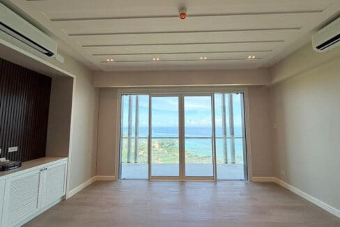 Living area with sea view balcony and wood plank flooring at Aruga Resort