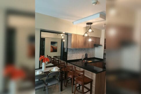 Dining table beside the custom bar counter with three bar chairs