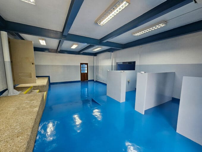 Open-plan 115 sqm ground-floor office space for rent at Cebu Yacht Club, Lapu-Lapu City, with blue epoxy flooring and low partitions