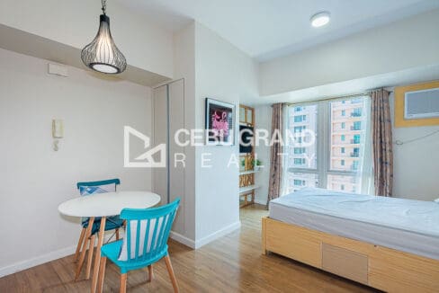 Kitchen with range hood, gas cooktop and refrigerator beside the dining table at the studio for rent at Solinea Tower 2