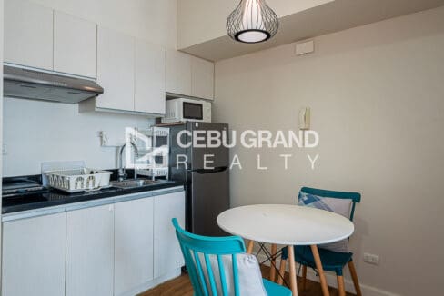 Wall-mounted television on rattan shelving beside the city-view window at the studio for rent at Solinea Tower 2