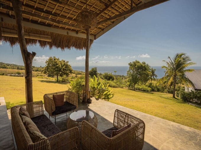 Covered lounge pavilion with rattan seating looking over the lawn to the sea at the operating resort for sale in Oslob, Cebu