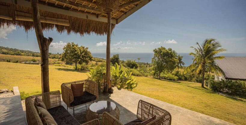 Covered lounge pavilion with rattan seating looking over the lawn to the sea at the operating resort for sale in Oslob, Cebu
