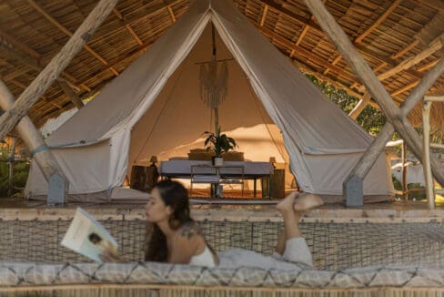 Guest relaxing on a daybed in front of a canvas bell tent at the resort for sale in Oslob, Cebu