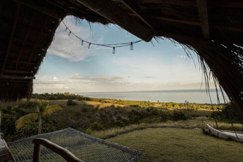 Sea view from a shaded deck with hammock and string lights at the resort for sale in Oslob, Cebu