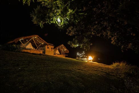 Glamping tents and outdoor fire pit lit at night at the resort for sale in Oslob, Cebu